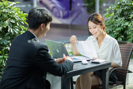 商务白天面试求职者的女领导户外看简历问问题摄影图配图