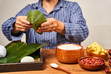 粽叶糯米摄影照片_包粽子端午节粽叶端午材料裹粽子摄影图配图