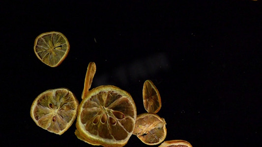 黑色主图素材摄影照片_飞起的柠檬片黑色背景素材