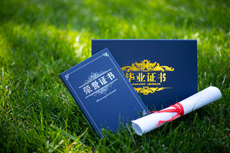 业荣誉证书文件展摄影照片_毕业季暑期毕业证书绿地上展示摄影图配图