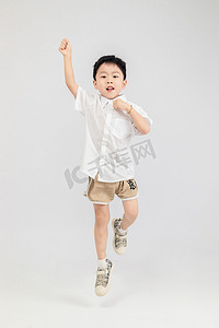 运动男孩摄影照片_儿童节白天男孩室内跳跃摄影图配图