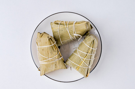 小吃中国摄影照片_夏天传统美食白天一盘粽子室内餐桌静物摆拍摄影图配图
