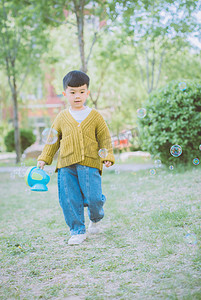 儿童节泡泡摄影照片_玩耍白天男孩户外散步摄影图配图