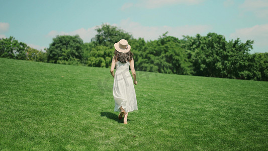 意境人物摄影照片_夏天女生美女在草坪上奔跑背影唯美意境