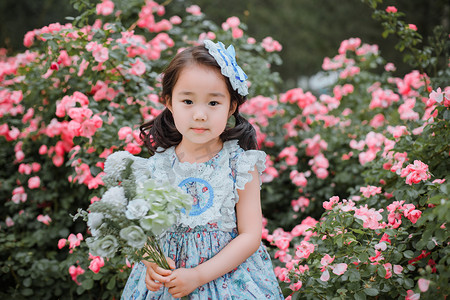 儿童节女孩摄影照片_人物形象白天女孩花园手捧鲜花摄影图配图