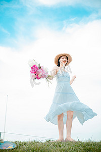 文艺清新白天穿白裙子的美女户外草坪拿着鲜花转圈摄影图配图