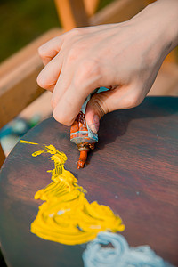 画画写生调色白天挤颜料的手户外挤颜料摄影图配图