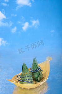 小吃特产摄影照片_美食端午节粽子蓝天下的小船坐船摄影图配图