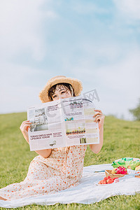 夏天文艺白天野餐的美女白天拿报纸挡脸摄影图配图