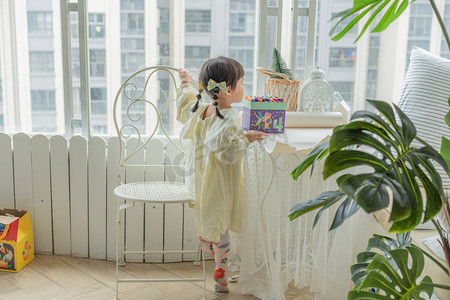 儿童玩玩具摄影照片_画画女孩下午儿童阳台爬椅子摄影图配图