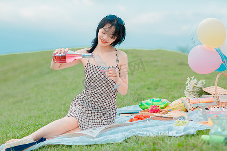 文艺夏天白天野餐美女草地倒酒摄影图配图