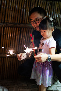 虎年国庆节摄影照片_玩烟花的父女夜晚室外摄影图配图