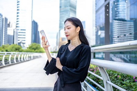 女职业摄影照片_商务金融白天商务女青年人行桥看手机摄影图配图