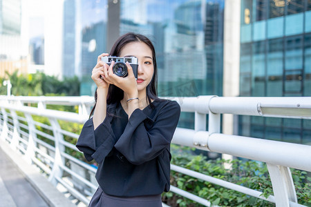 商务人像下午白领女性人行桥用相机拍照摄影图配图