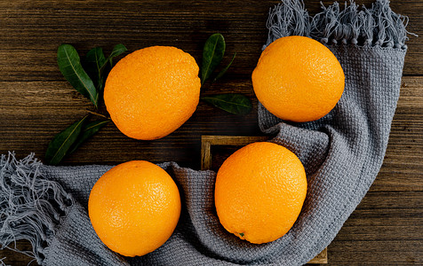 夏季新鲜水果夜晚四个橙子室内桌子静物摆拍摄影图配图