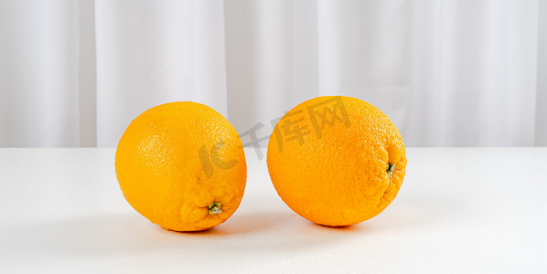 橙子生鲜摄影照片_夏天室内水果白天两个橙子室内餐桌静物摆拍摄影图配图