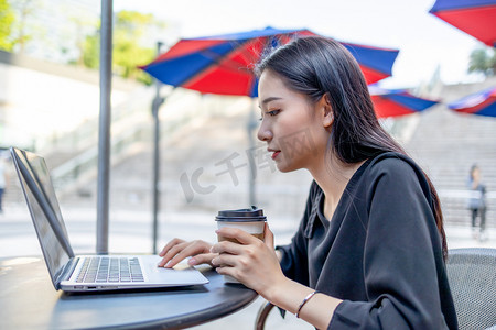 商务人像下午商务女性咖啡店拿着咖啡玩电脑摄影图配图