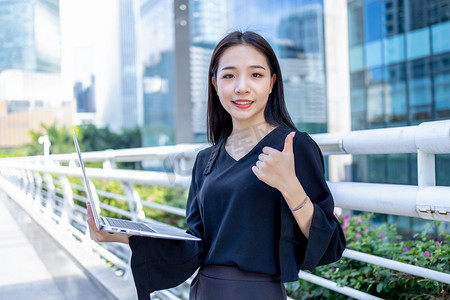 商务人像白天职场女性写字楼手拿笔记本点赞摄影图配图