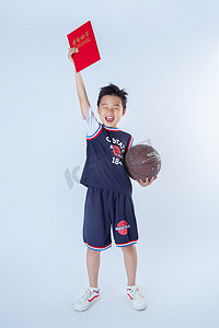 打篮球背景摄影照片_运动男孩白天打球的孩子室内白背景拿着荣誉证书摄影图配图