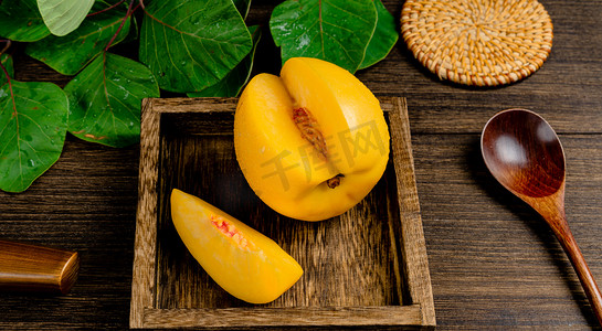 黄桃果农摄影照片_夏天美味水果白天一个黄桃室内部分切开后的黄桃摄影图配图