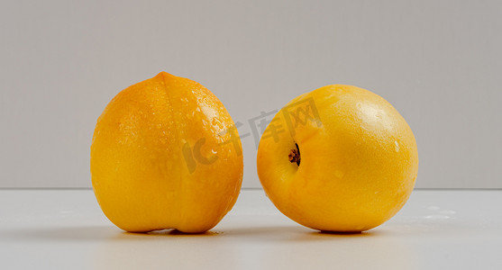 黄桃实物摄影照片_夏天美味水果白天两个黄桃室内静物摆拍摄影图配图