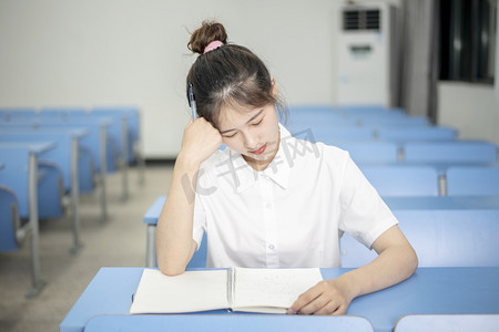 高考晚上一个女学生在教室思考问题摄影图配图