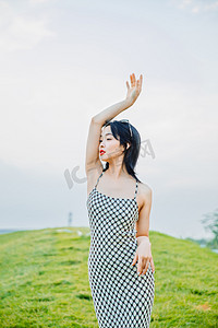 野餐白天穿长裙的美女户外草地抬起手臂摄影图配图
