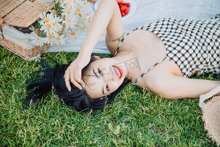 春游的摄影照片_野餐白天穿着长裙的美女草坪躺在地上摄影图配图