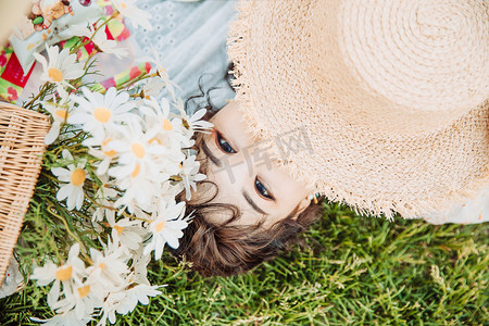 野餐白天躺在草地的美女户外用帽子挡眼睛摄影图配图