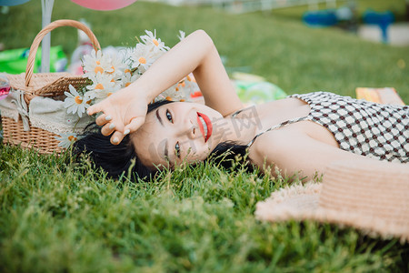躺在草地摄影照片_野餐白天躺在地上的美女户外手扶额头摄影图配图