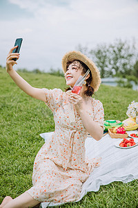 野餐郊游白天穿着碎花裙的美女户外草地端着酒杯自拍摄影图配图