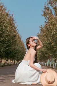 文艺摄影照片_夏天文艺白天穿着白色长裙的美女户外用手挡住阳光摄影图配图