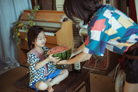 儿童儿童节快乐摄影照片_夏日亲子白天母子两人室内妈妈给西瓜摄影图配图