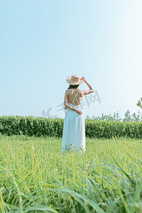 文艺美女夏天白天穿着白色长裙的美女户外站在田野里摄影图配图