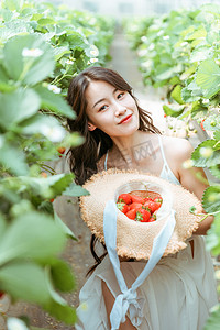 文艺夏天白天穿着白色长裙的美女户外采摘园捧着草莓摄影图配图
