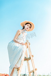 夏天文艺美女白天穿着长裙的美女户外爬梯子摄影图配图