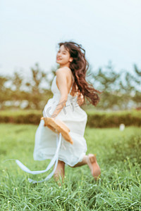 田野国风摄影照片_夏天文艺白天穿着白色长裙的美女户外田野奔跑摄影图配图