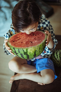 快乐的儿童节摄影照片_夏日儿童白天小朋友室内低头吃西瓜摄影图配图