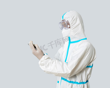 防疫疫情医生棚拍穿防护服看平板侧面摄影图配图