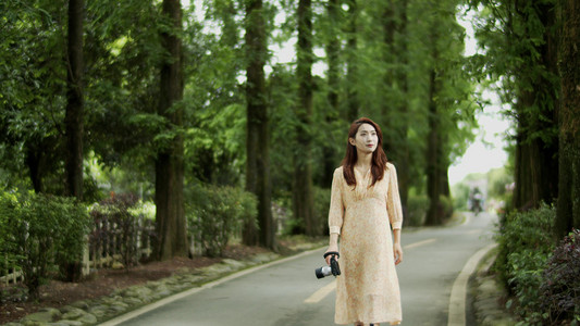 美女走在树林公路上拍照旅途中文艺