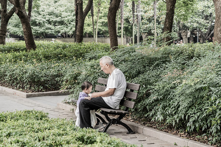 暑假班报名了摄影照片_公园里老人在照顾孙女