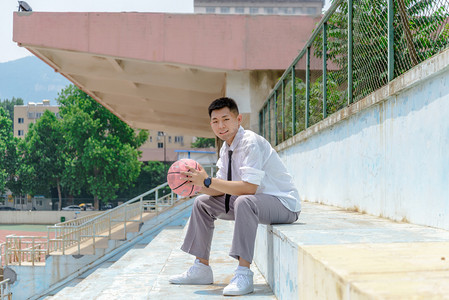 篮球胶囊摄影照片_人像白天大学女生台阶拿着篮球摄影图配图