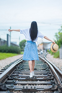 飘逸白裙女孩摄影照片_铁轨上行走的女孩