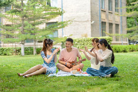 夏天校园摄影照片_人像白天四个人草地弹琴摄影图配图