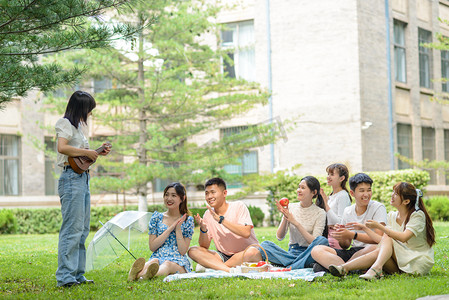 校园友情摄影照片_人物白天七个人草地看表演摄影图配图