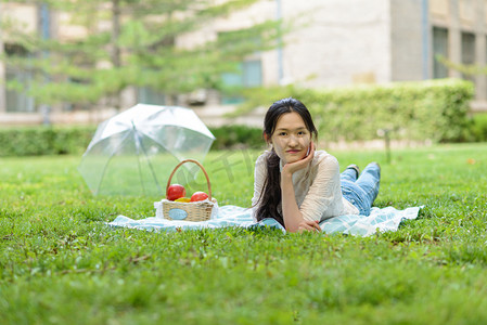 友情摄影照片_人像白天一个美女草地趴着摄影图配图