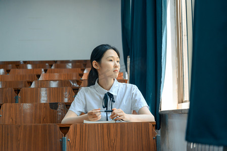 人像白天女大学生教室看向远方摄影图配图