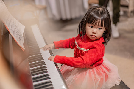 弹钢琴孩子摄影照片_钢琴女孩下午儿童弹钢琴弹摄影图配图