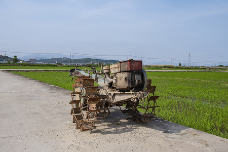 稻秧摄影照片_路上的割稻机下午割稻机农村无摄影图配图