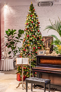 钢琴演奏节目单摄影照片_圣诞树夜晚圣诞树钢琴室内静物摄影图配图